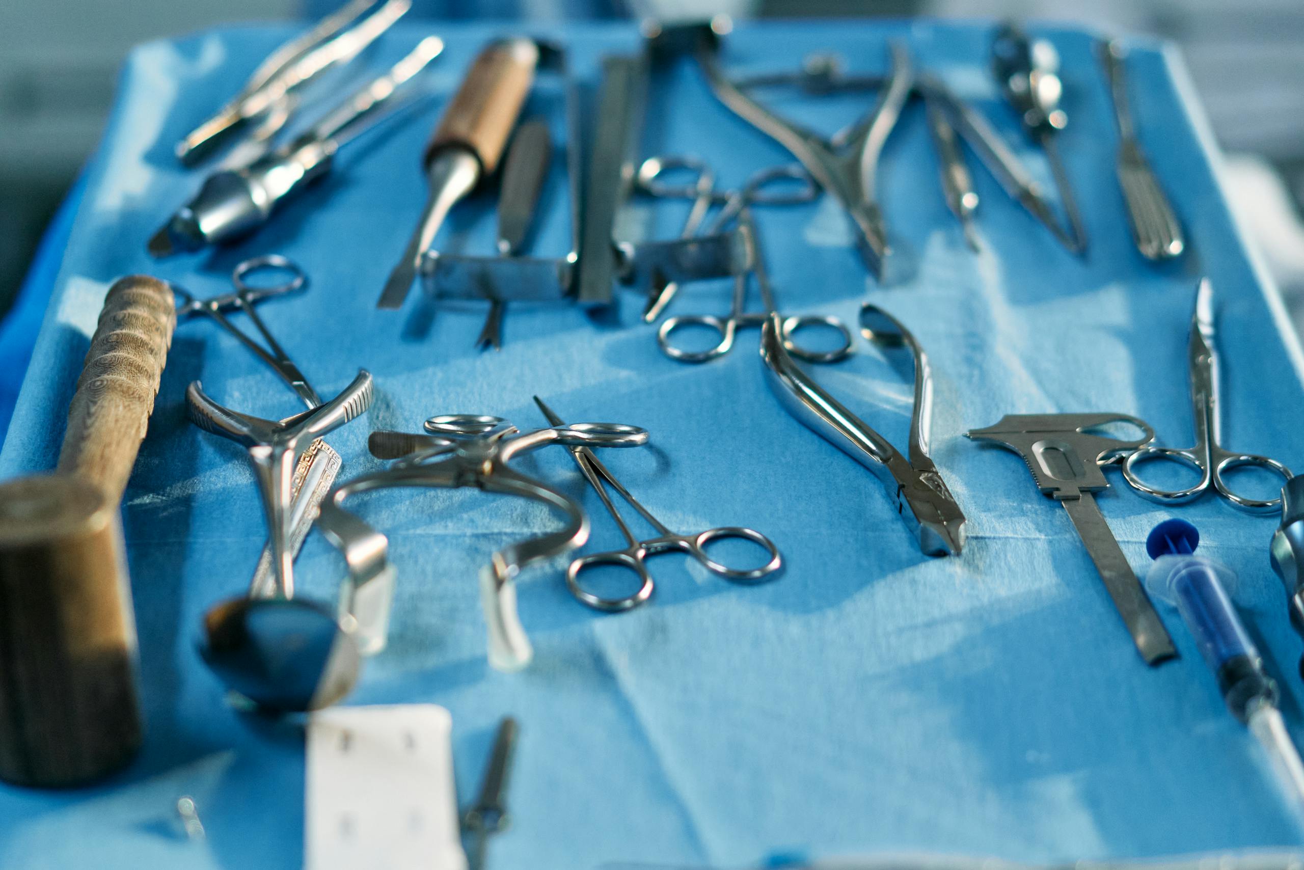 Close-up of various sterilized surgical tools laid out on a blue surface, ready for medical procedures.